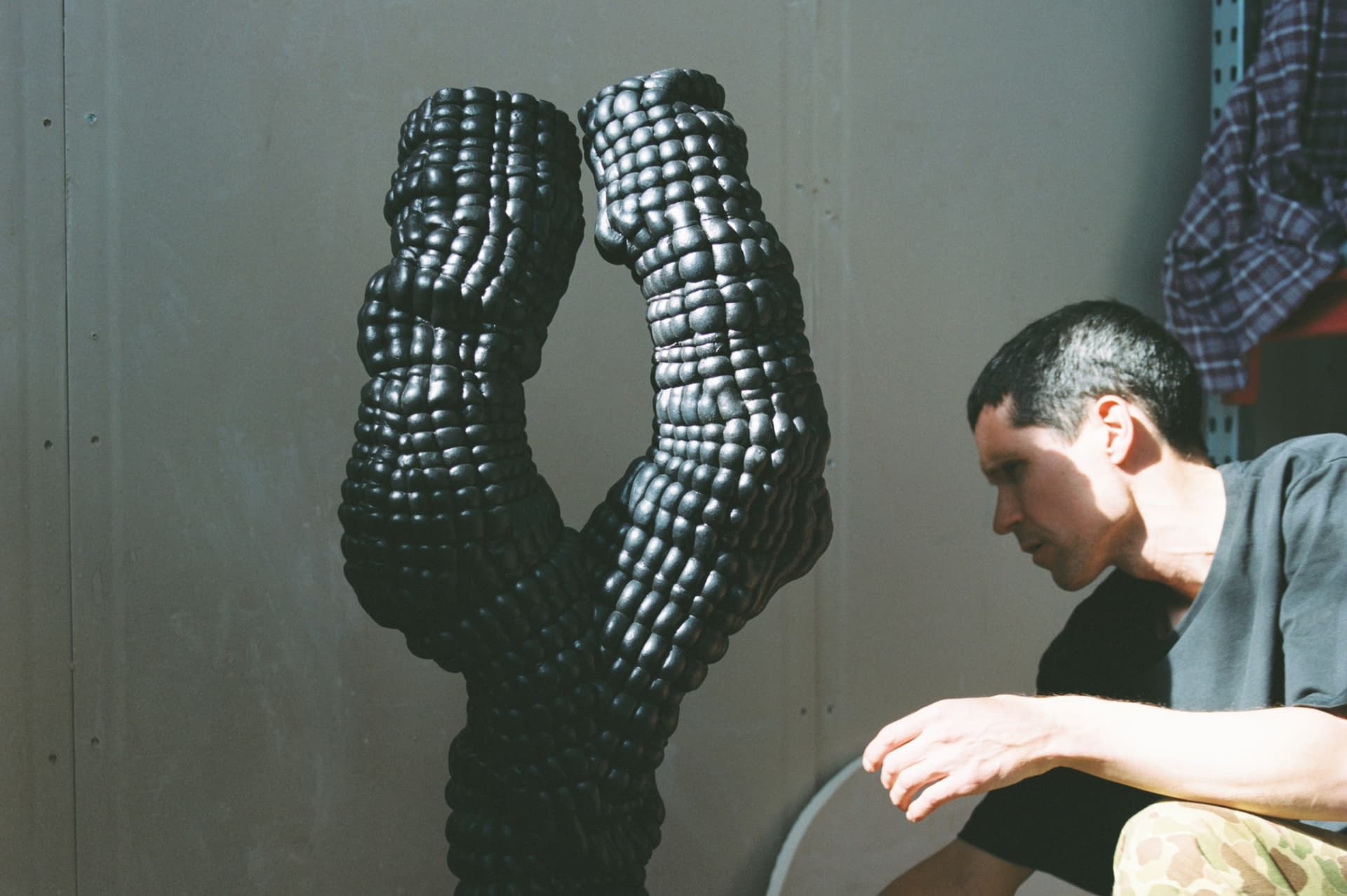 Artist Anton Alvarez in his studio with dark ceramic sculpture