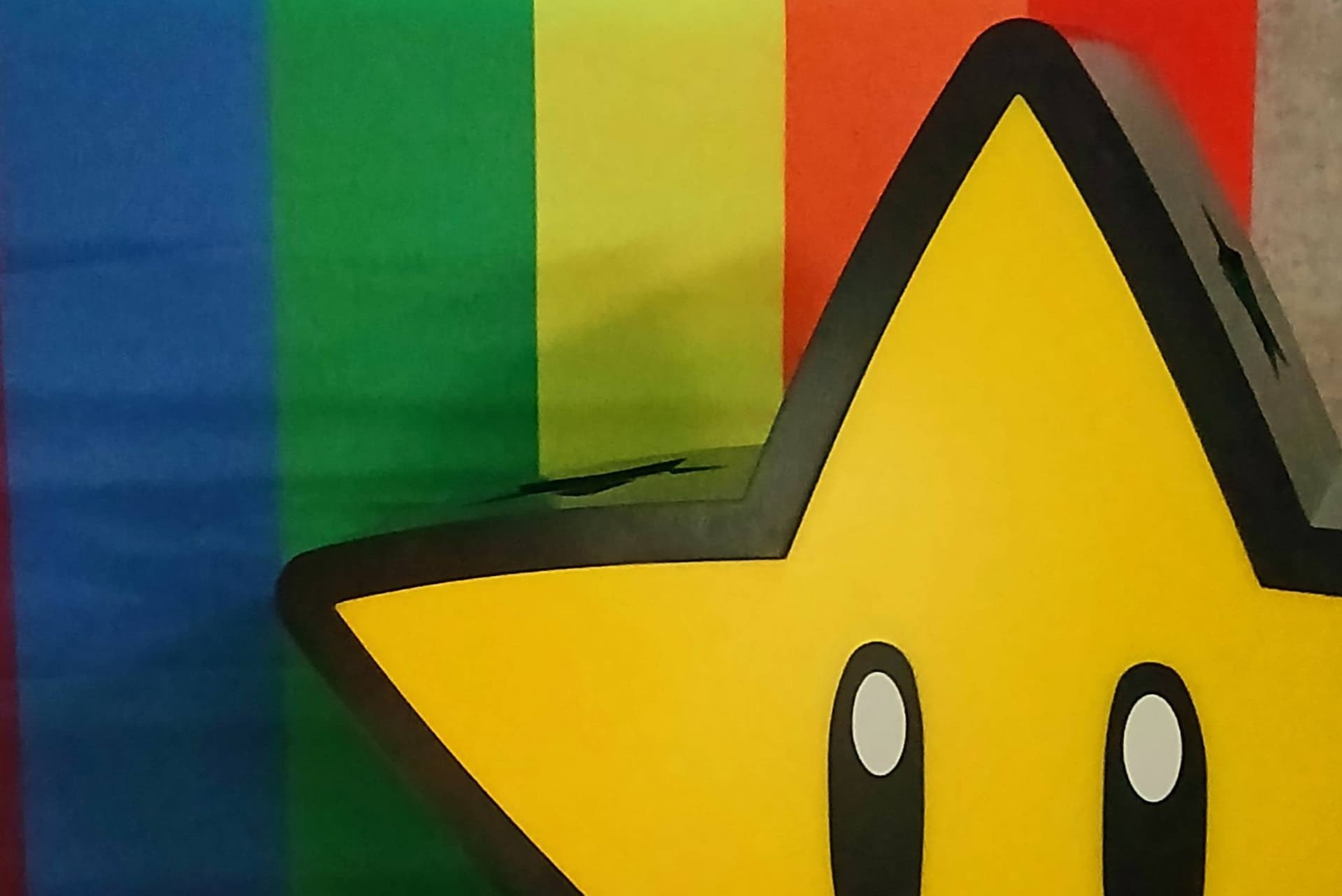 Taustalla sateenkaarilippu, etualalla näkyy osittain Mario-pelisarjan tähtihahmo