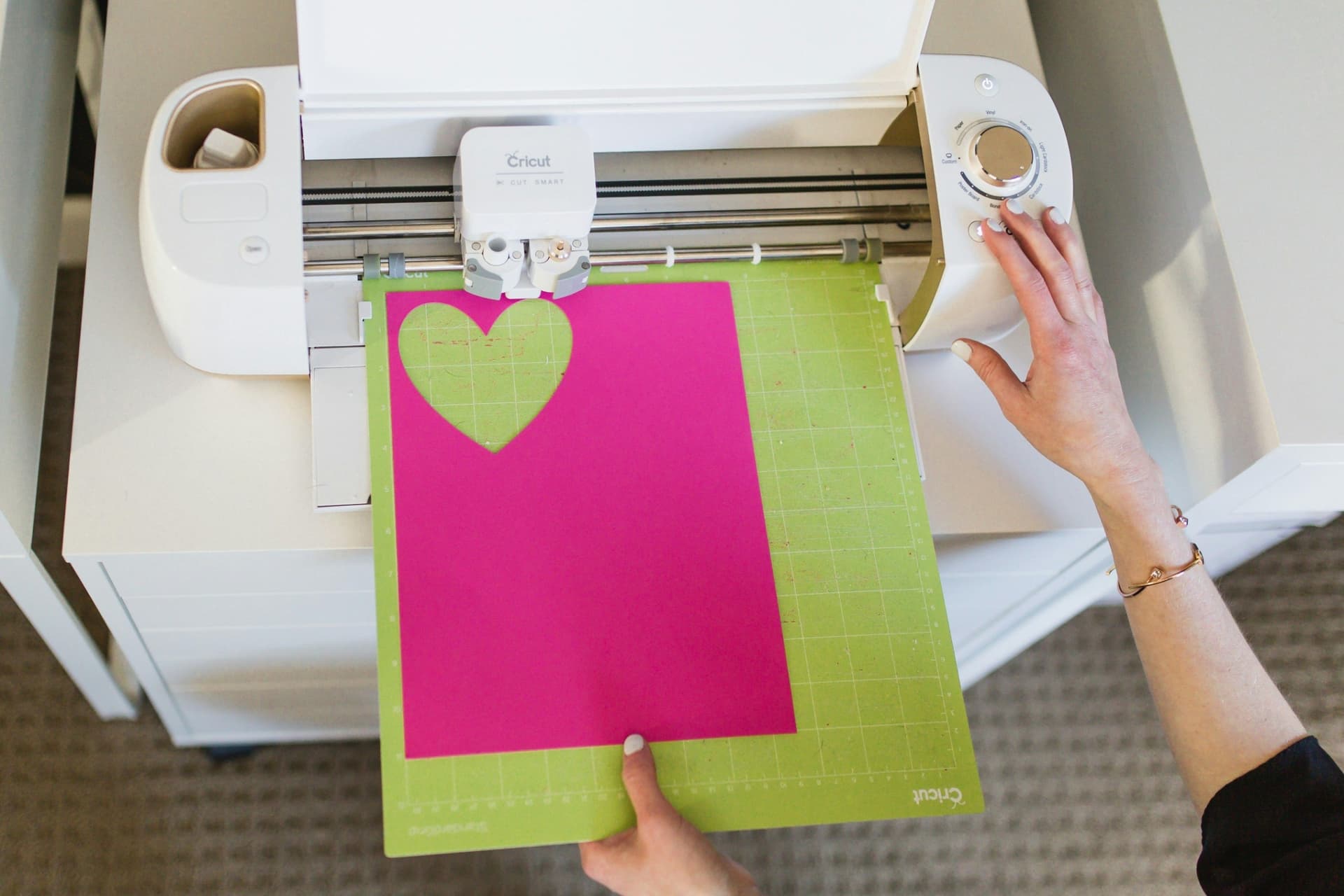 Henkilö syöttää leikattavaa materiaalia Cricut-leikkuriin