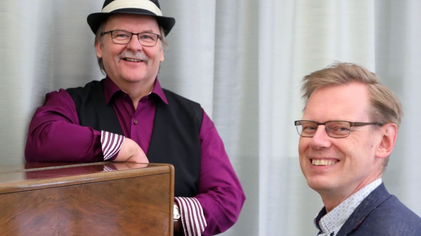 2 keski-ikäistä miestä hymyilee kameralle.