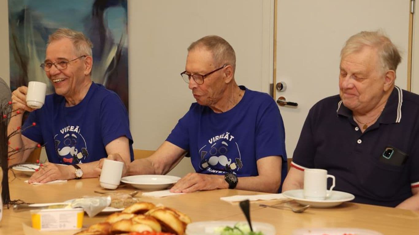 Eläkeikäiset miehet keskustelevat kahvipöydässä